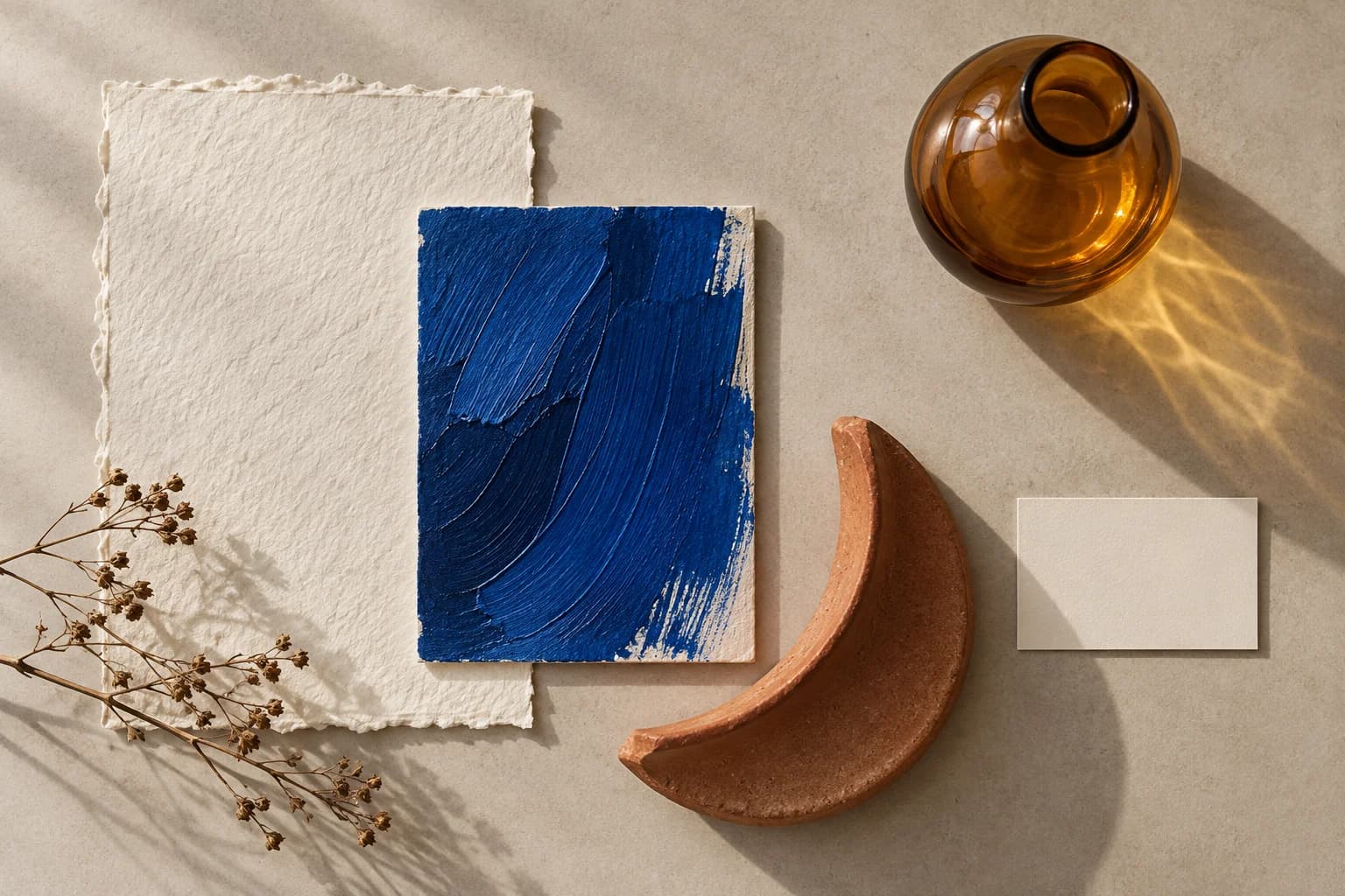 Ivory paper, cobalt brushwork, terracotta ceramic and amber glass arranged as material references