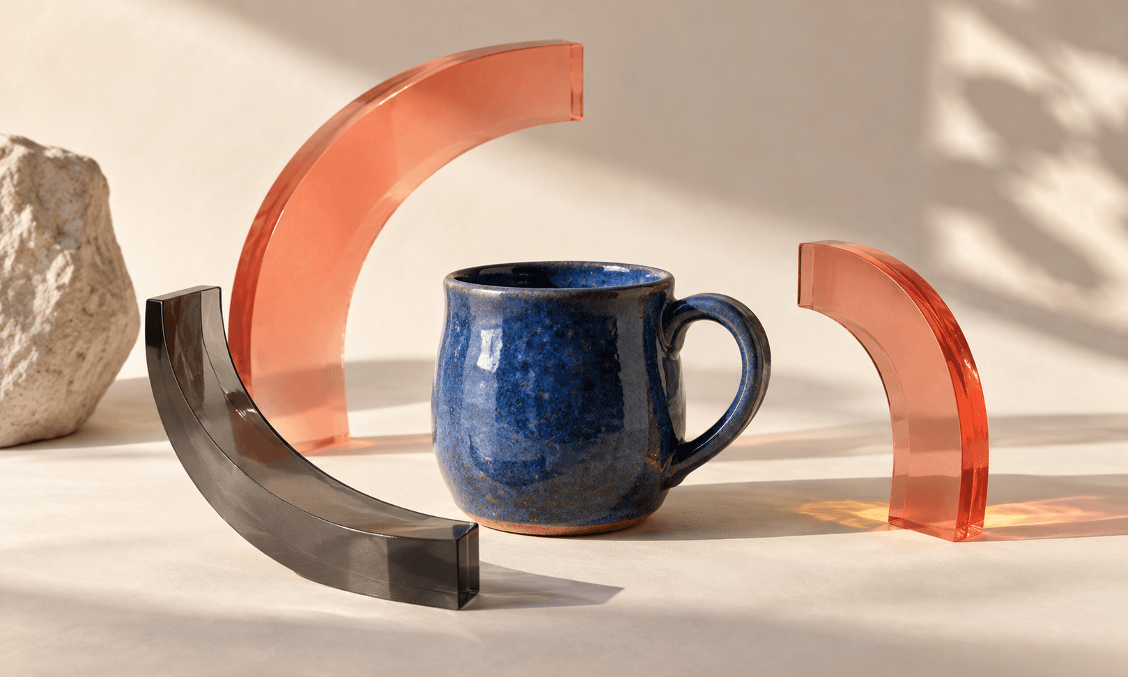 A cobalt blue handmade cup with coral and charcoal sculptural paper forms