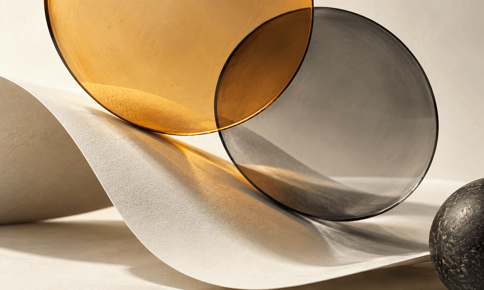 Amber and smoke-colored glass discs overlap above curved ivory paper
