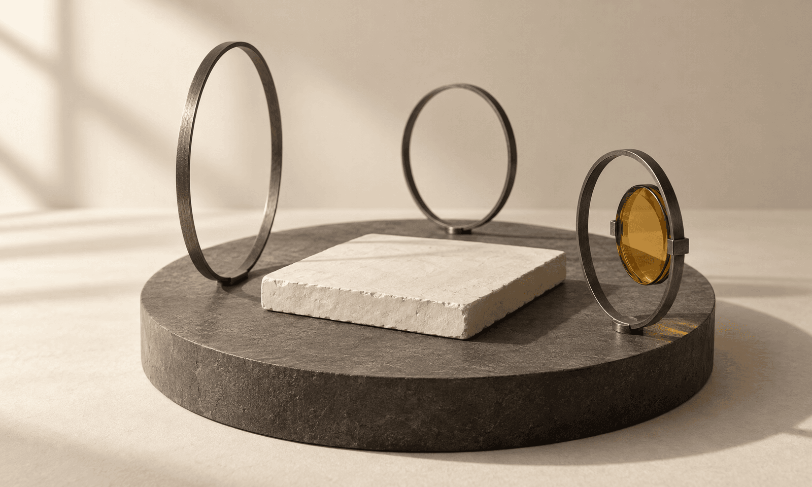 Tres finos anillos de grafito rodean una losa de cerámica marfil sobre un disco color carbón; uno de los anillos sostiene una lente ámbar