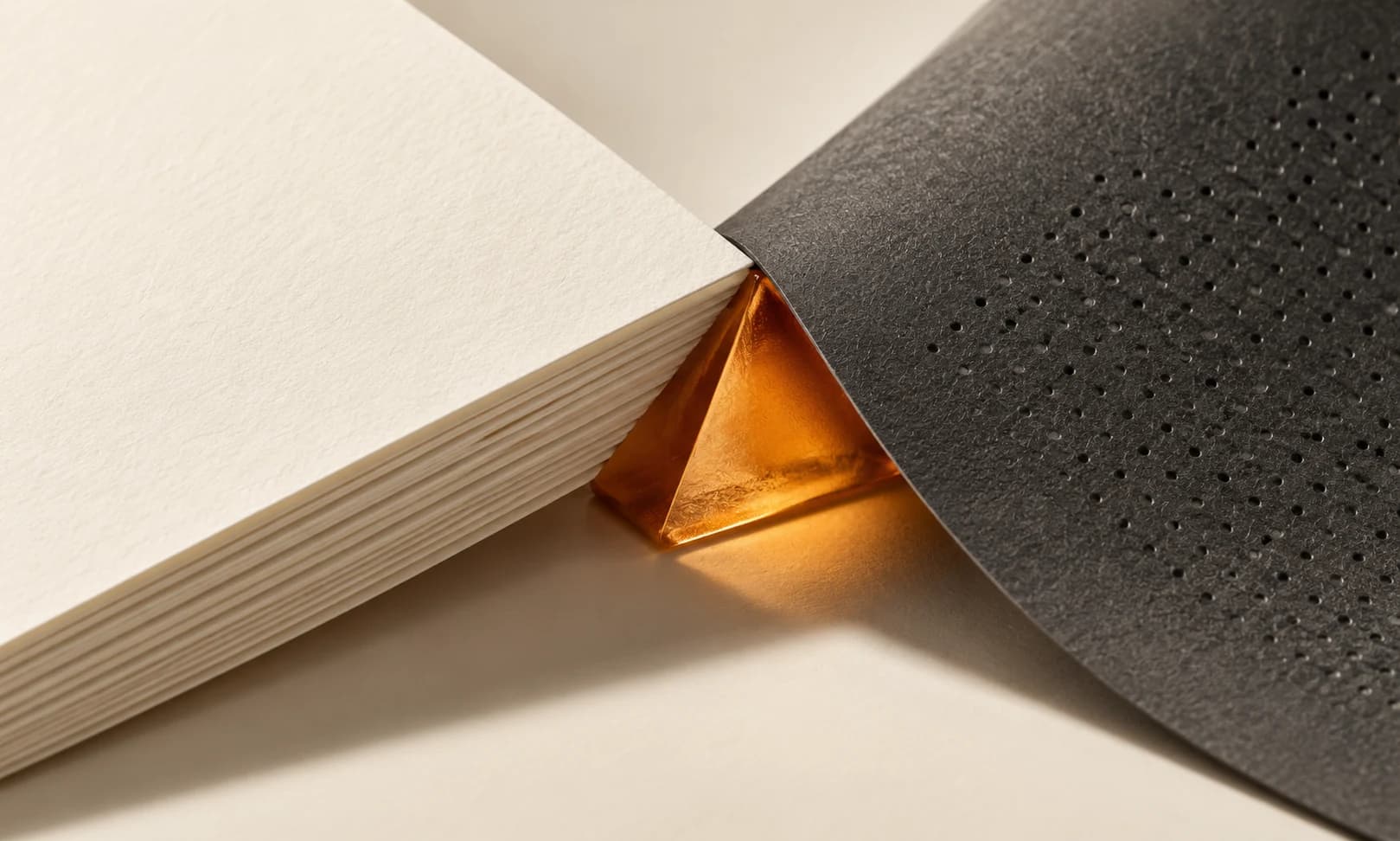 Two parallel matte picture-like planes with a fine charcoal edge and amber detail on ivory.