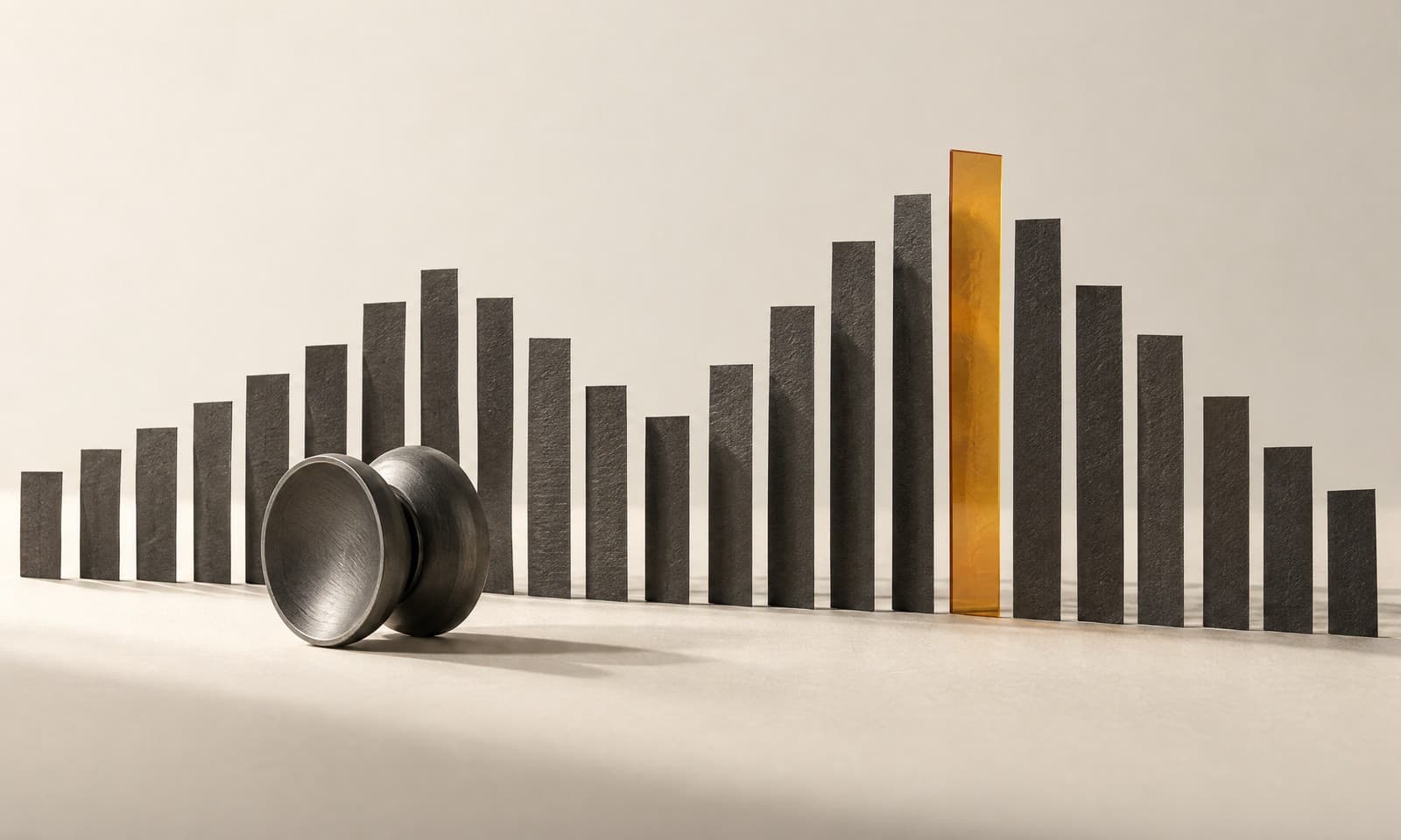 A row of charcoal paper strips rising and falling like a sound wave, one amber strip at the peak and a graphite yo-yo resting in front