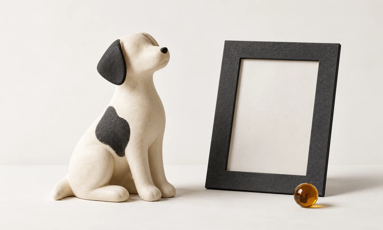 Ivory ceramic dog beside a charcoal portrait frame