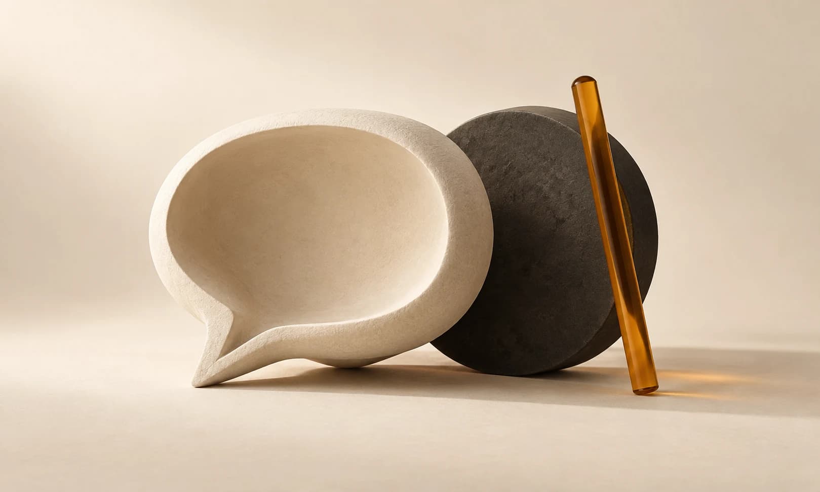 An ivory sculptural loop casting a charcoal shadow beside one amber bead