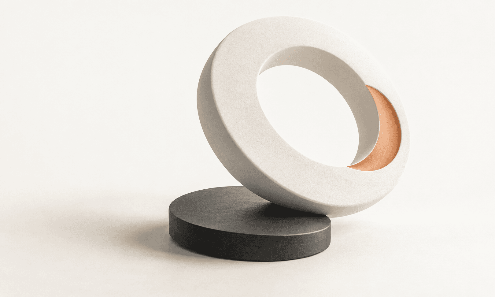 An ivory ceramic ring with an apricot inset balances on a charcoal disk