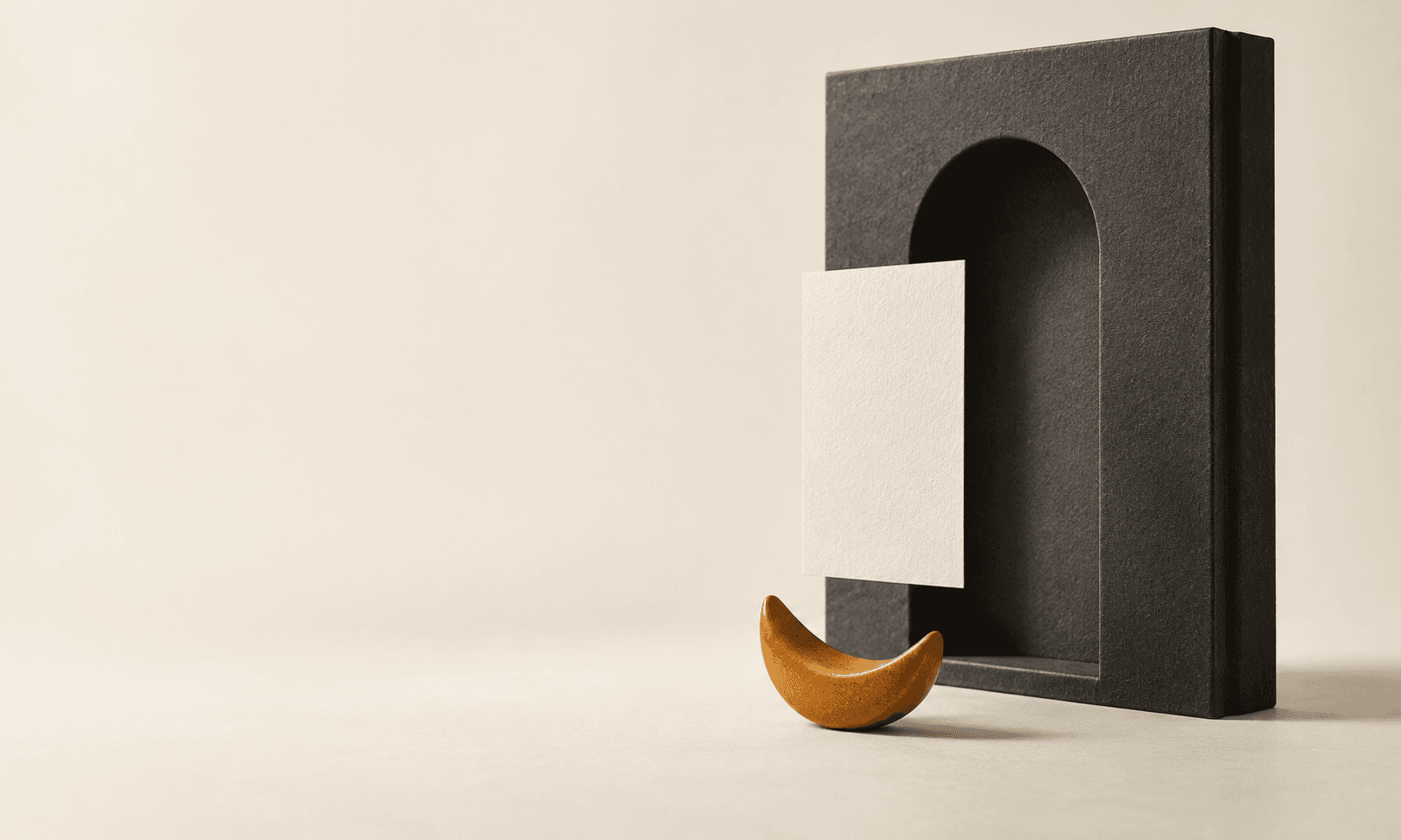 Escultura de libro gris carbón con rectángulo de papel marfil y creciente ámbar