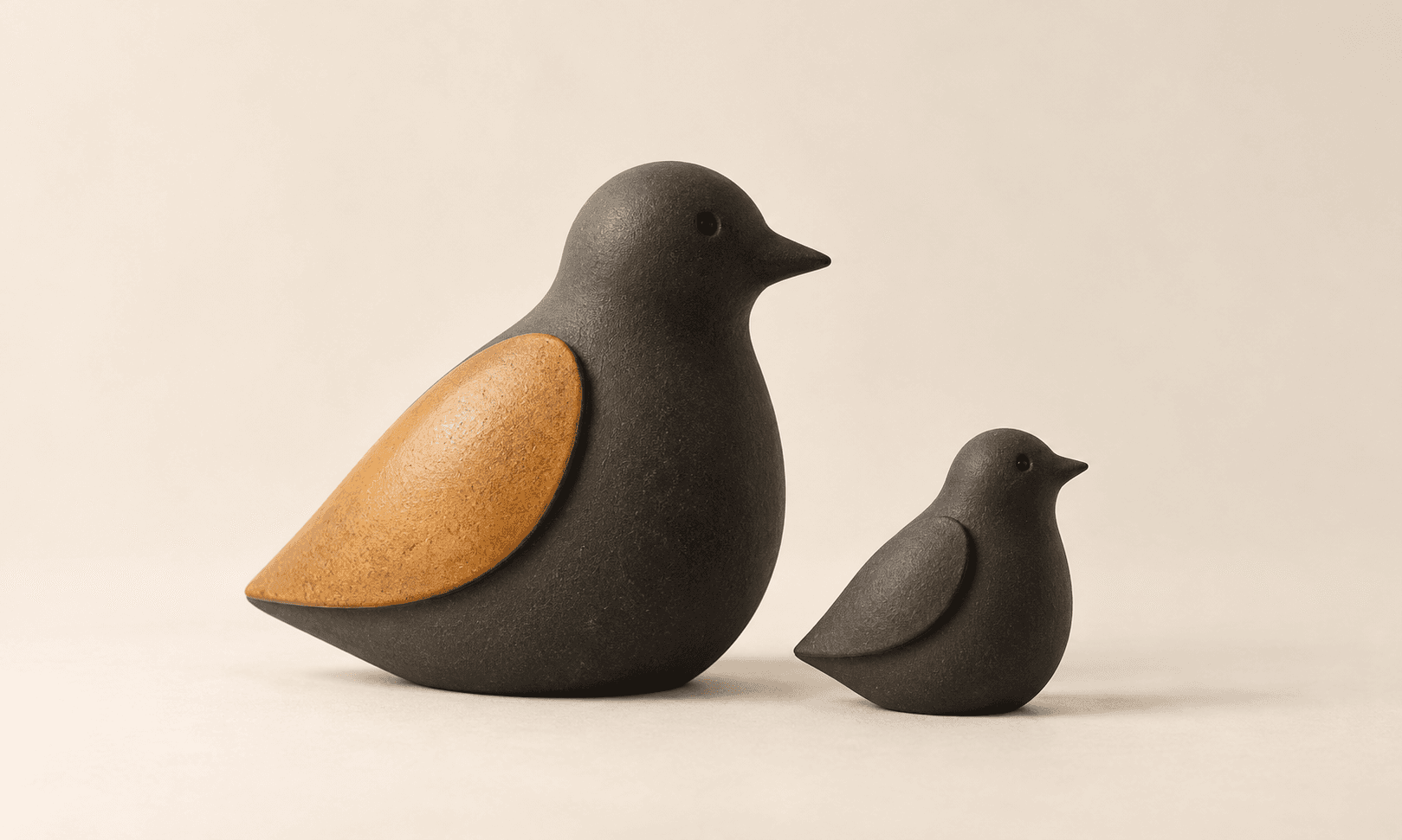 Two charcoal ceramic bird sculptures, one with an amber wing